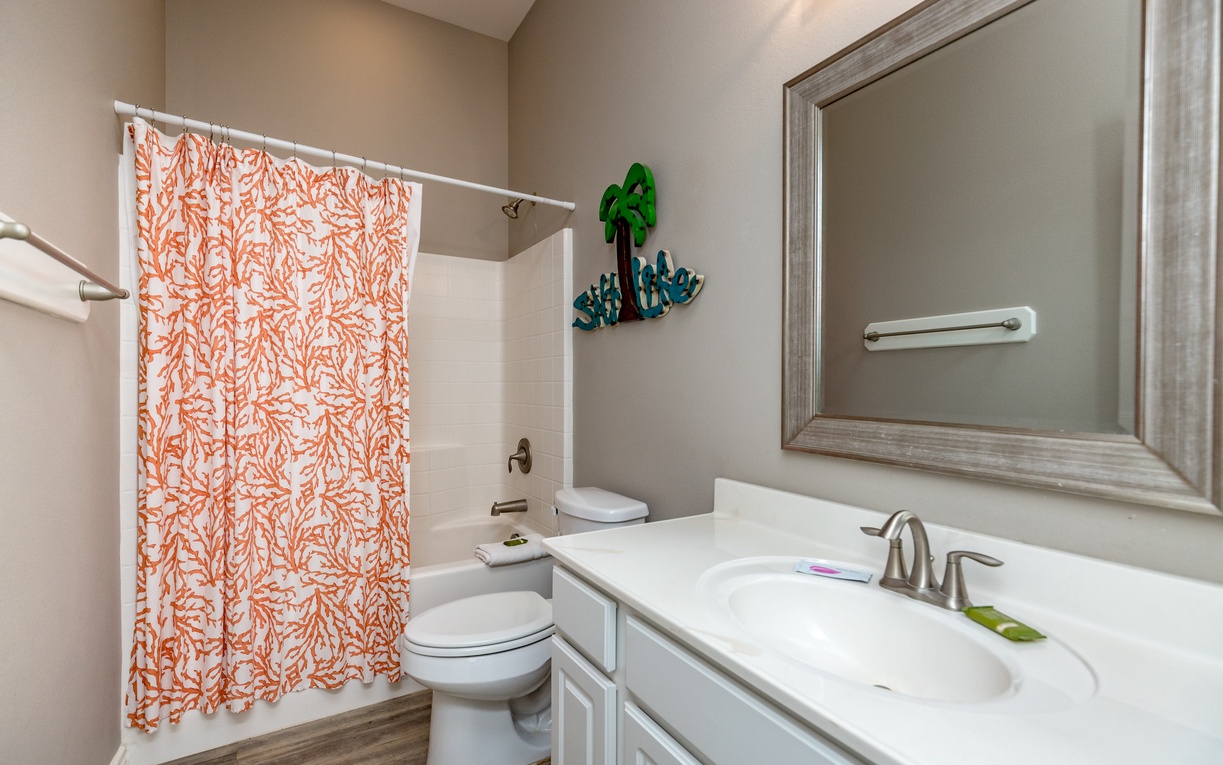 Freshen up in your bright, cheerful bathroom featuring a coral-patterned shower curtain and pristine white fixtures for comfortable mornings.