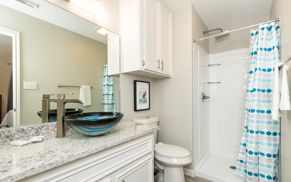 Step into your beautifully updated bathroom with stunning granite countertops, modern vessel sink, and refreshing tiled shower—coastal touches make it feel like home.