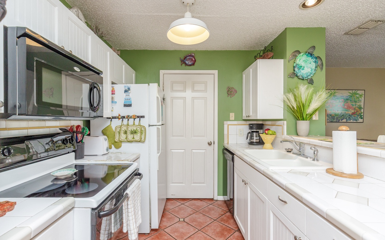 Your tropical-themed kitchen invites culinary adventures with full appliances, vibrant green walls, and charming coastal décor.