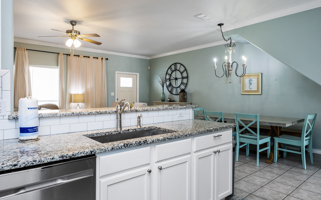 Your spacious kitchen flows seamlessly into the dining area, featuring granite countertops, modern appliances, and cheerful turquoise seating for memorable meals.