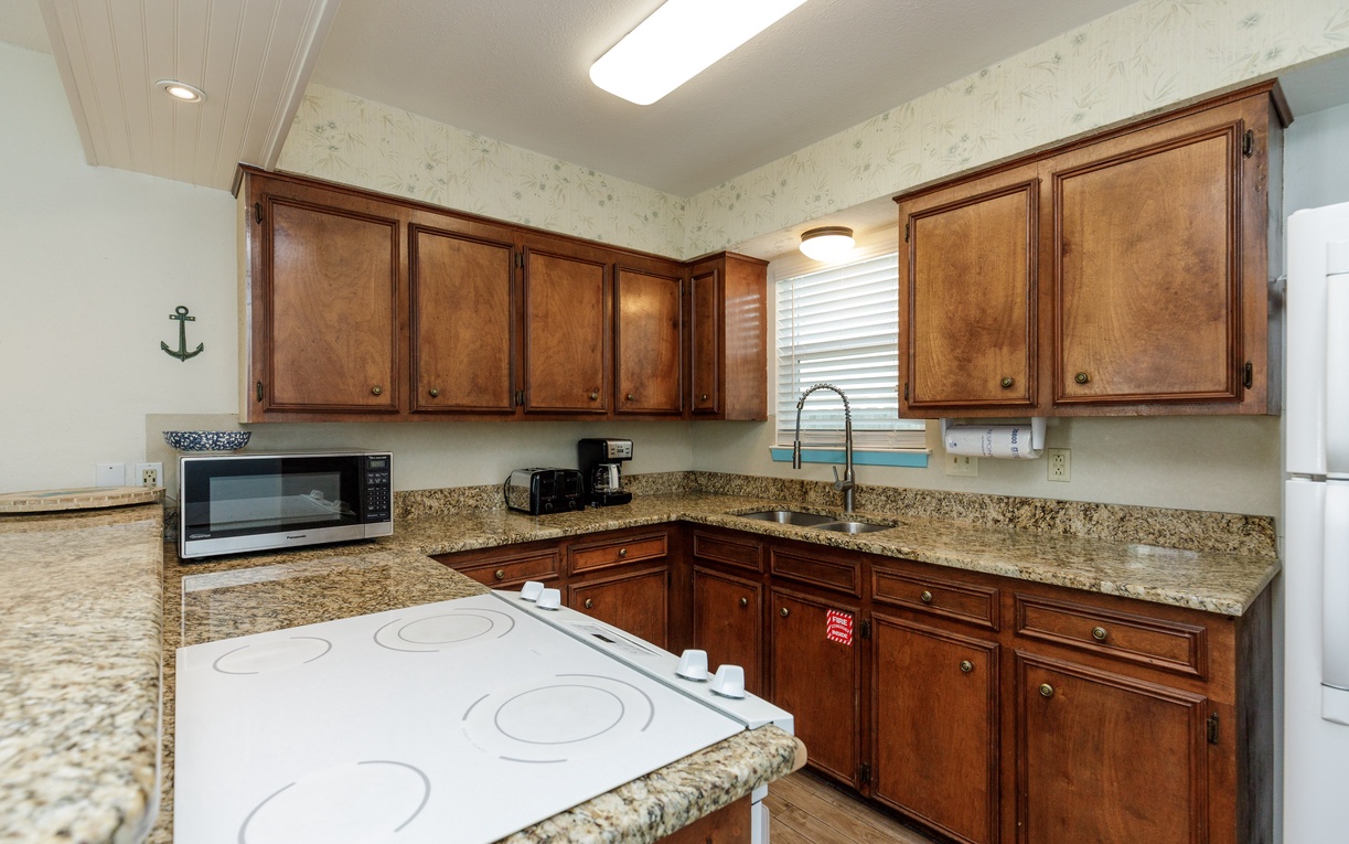 Your fully equipped kitchen features rich wooden cabinets, granite countertops, and modern appliances, creating the perfect space for preparing meals.