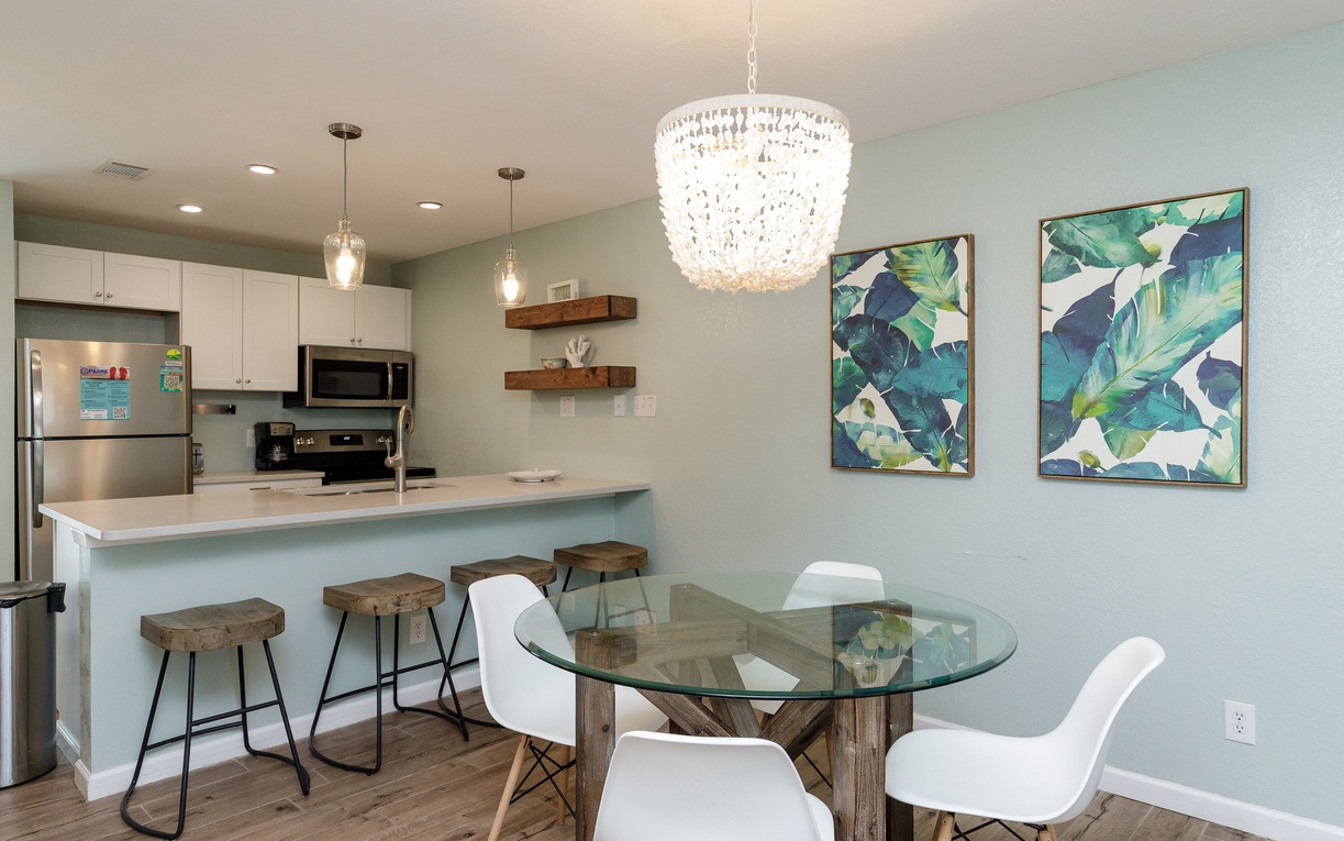 Your open kitchen flows seamlessly into an elegant dining space, where a stunning crystal chandelier illuminates meals shared around the glass table.
