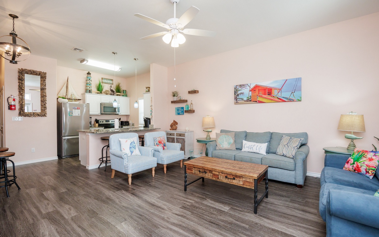 Relax in your bright coastal-themed living space with comfortable seating, a sleeper sofa, and a fully equipped kitchen ready for your vacation meals.