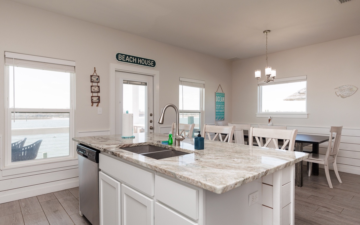Your bright coastal kitchen invites cooking with marble counters, beach views, and cozy dining for memorable vacation meals together.