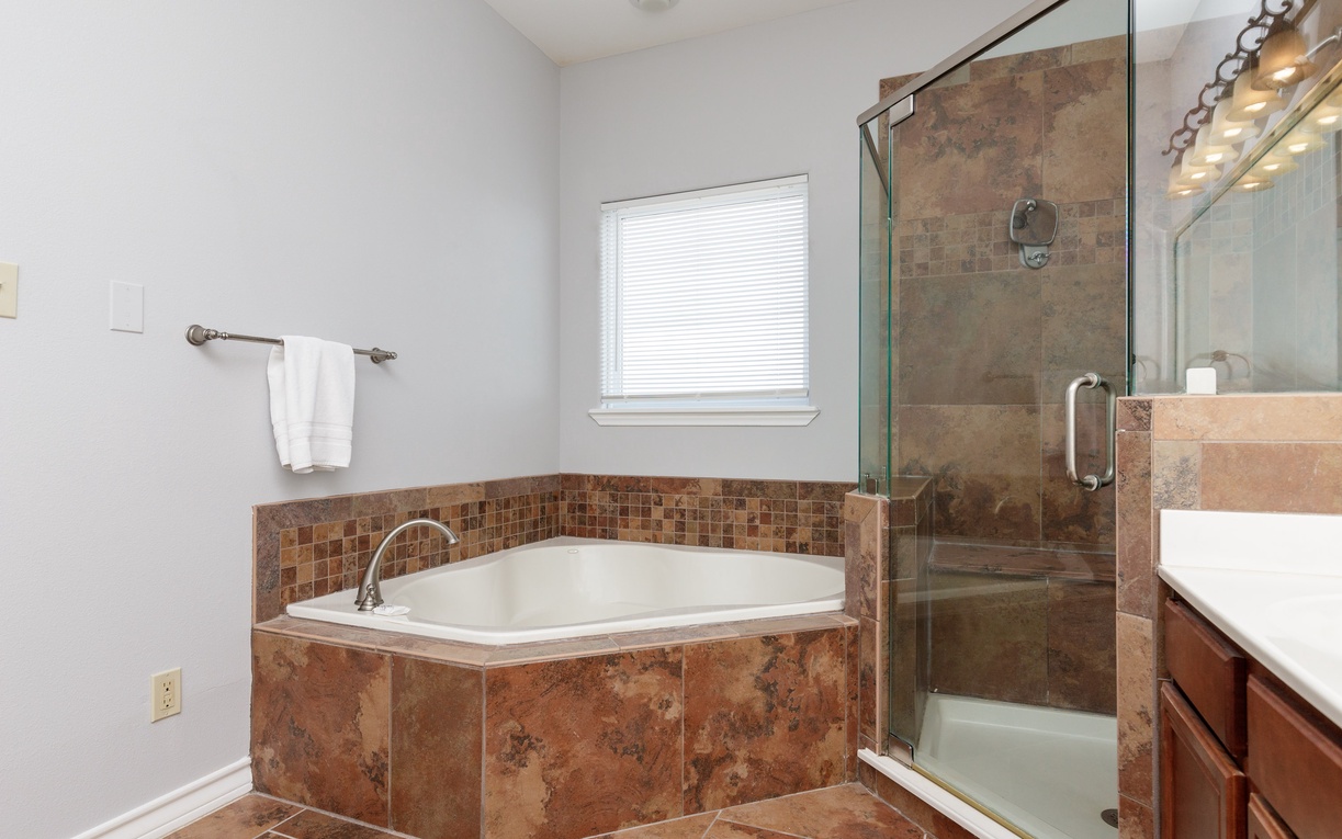 Luxurious bathroom with soaking tub and glass-enclosed shower, perfect for unwinding after your day of exploration.