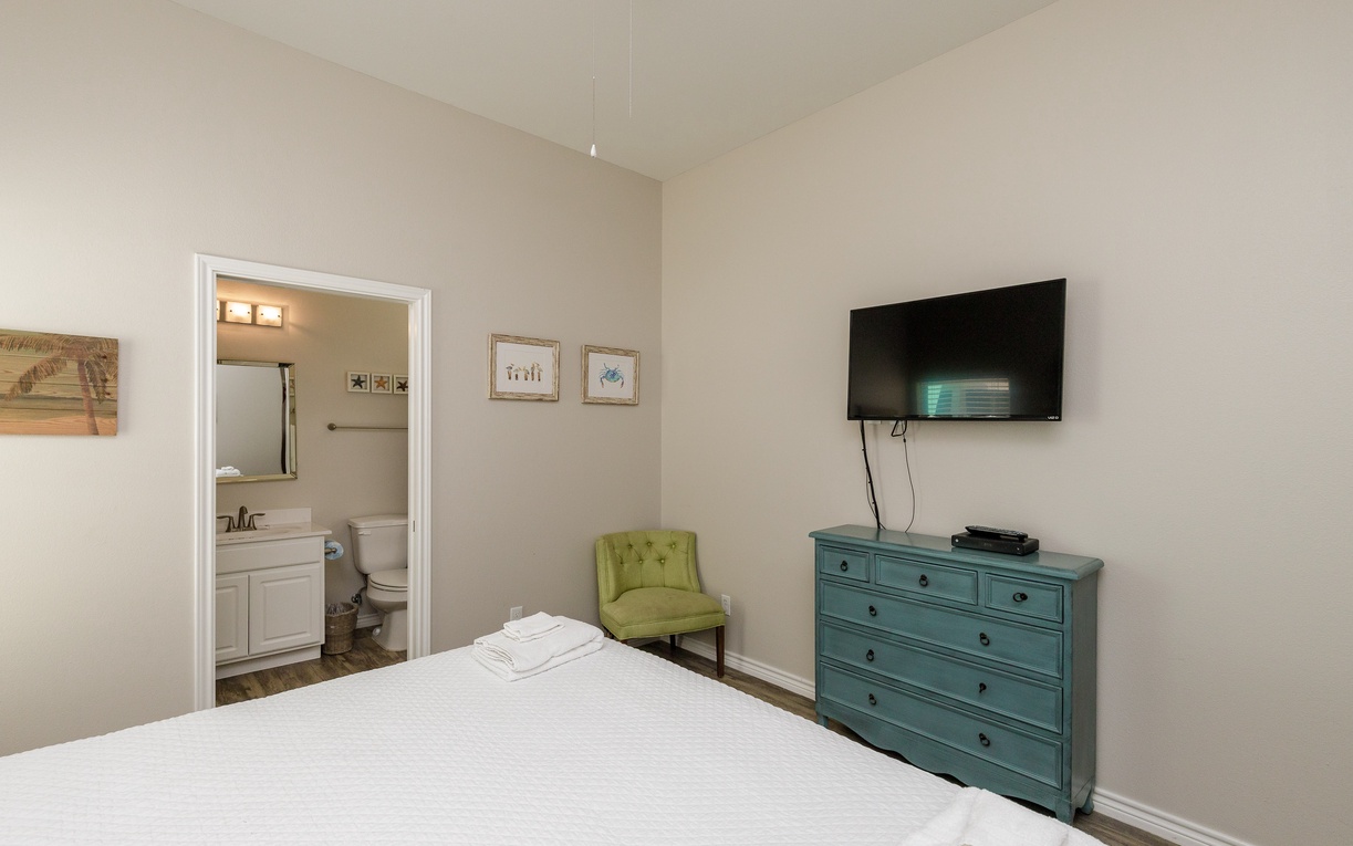 Settle into your peaceful bedroom with crisp linens, charming turquoise dresser, and cozy green accent chair for quiet moments.