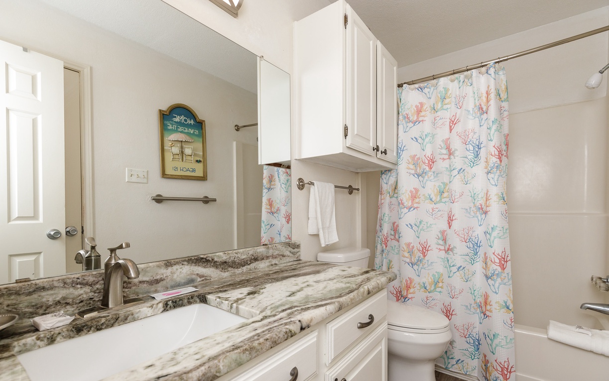 Your coastal bathroom features gorgeous granite counters and cheerful coral-pattern curtains, creating a beachy retreat for refreshing after sandy adventures.