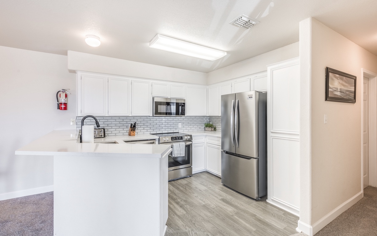 Your fully equipped kitchen features modern stainless steel appliances and pristine white cabinets, perfect for preparing memorable meals during your stay.