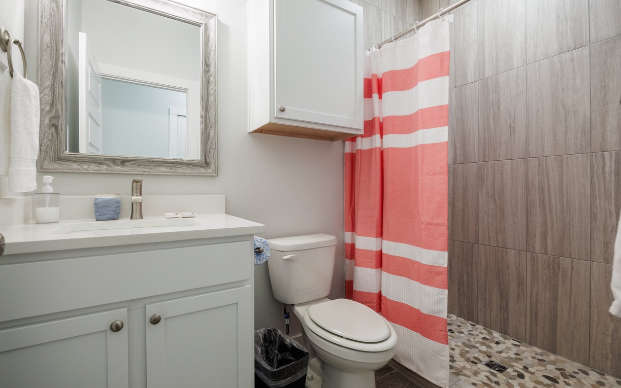 Step into your stylish private bathroom with modern wood-grain tiles and cheerful coral striped shower curtain.