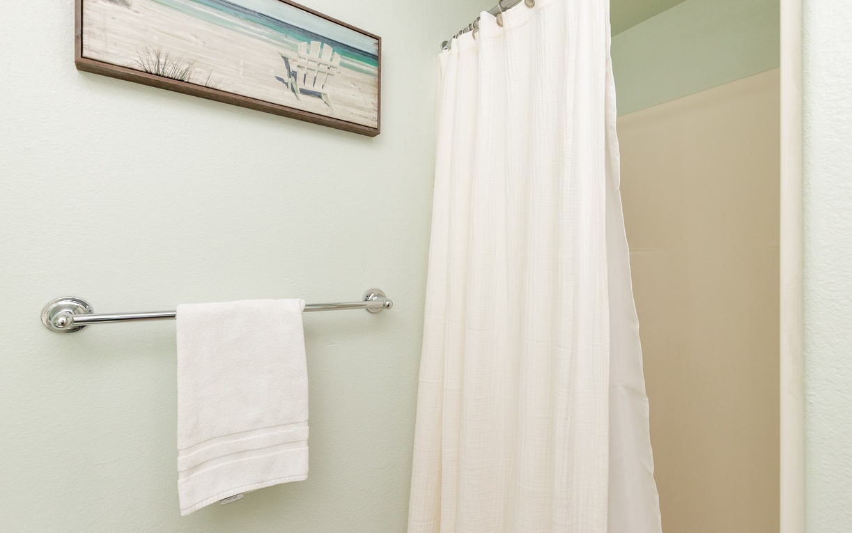 Fresh towels and coastal artwork create your serene bathroom retreat, complete with a private shower for refreshing moments.
