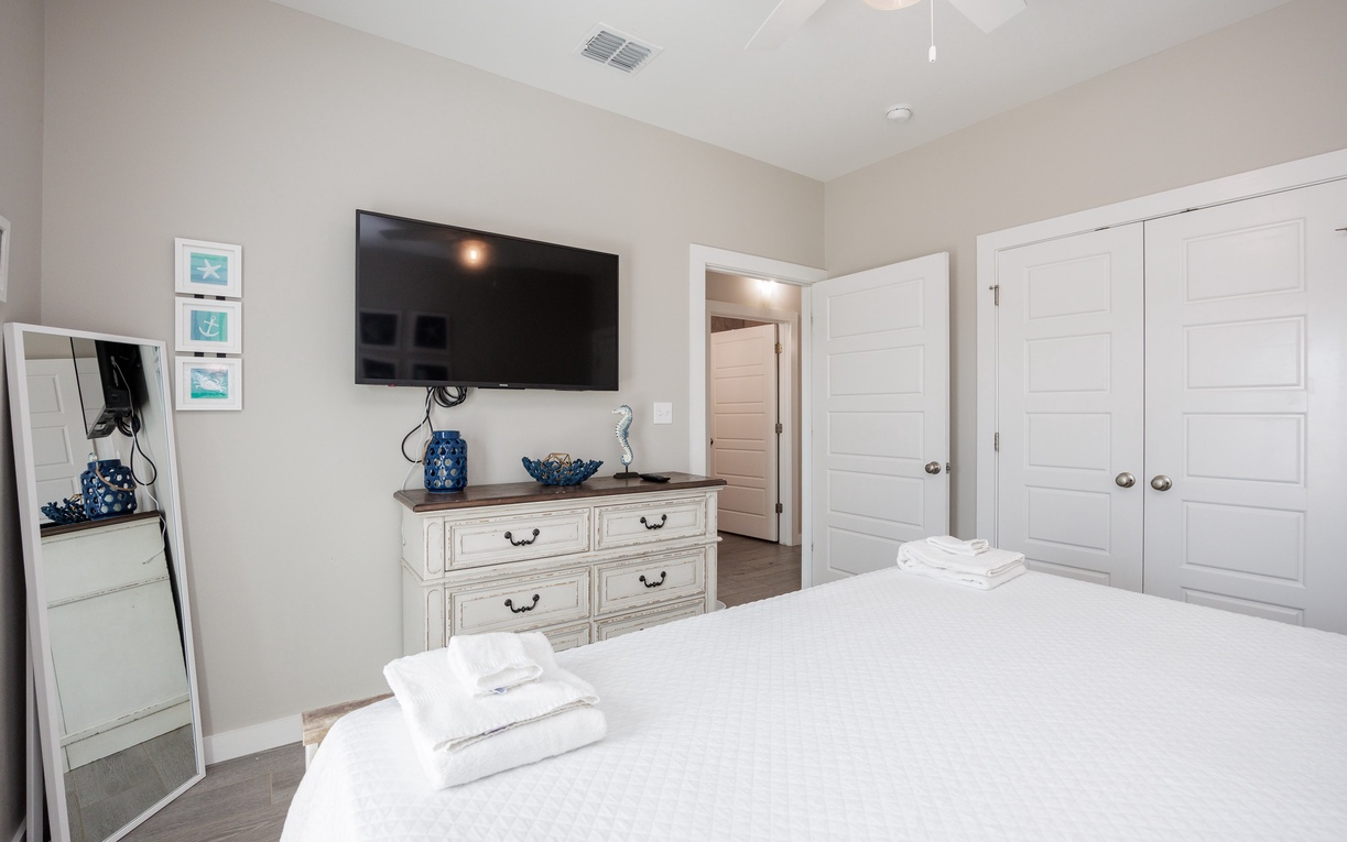 Unwind in your serene bedroom with fresh linens, wall-mounted TV, and coastal touches creating the perfect peaceful retreat.