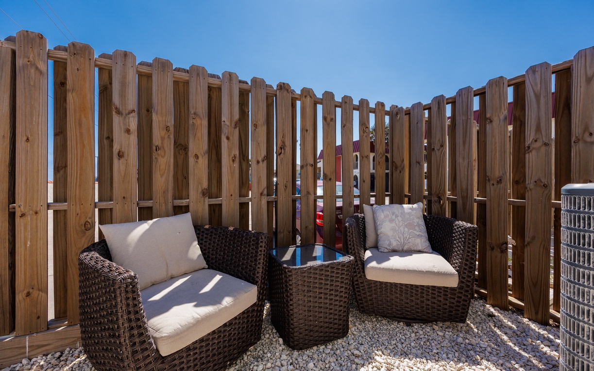 Relax in your private outdoor seating area with comfortable wicker chairs and soft cushions, perfect for morning coffee or evening unwind.