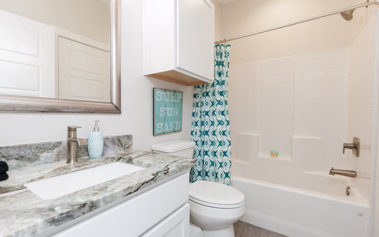 Your bright bathroom features marble countertops, a relaxing tub, and cheerful coastal touches that make getting ready a pleasure.