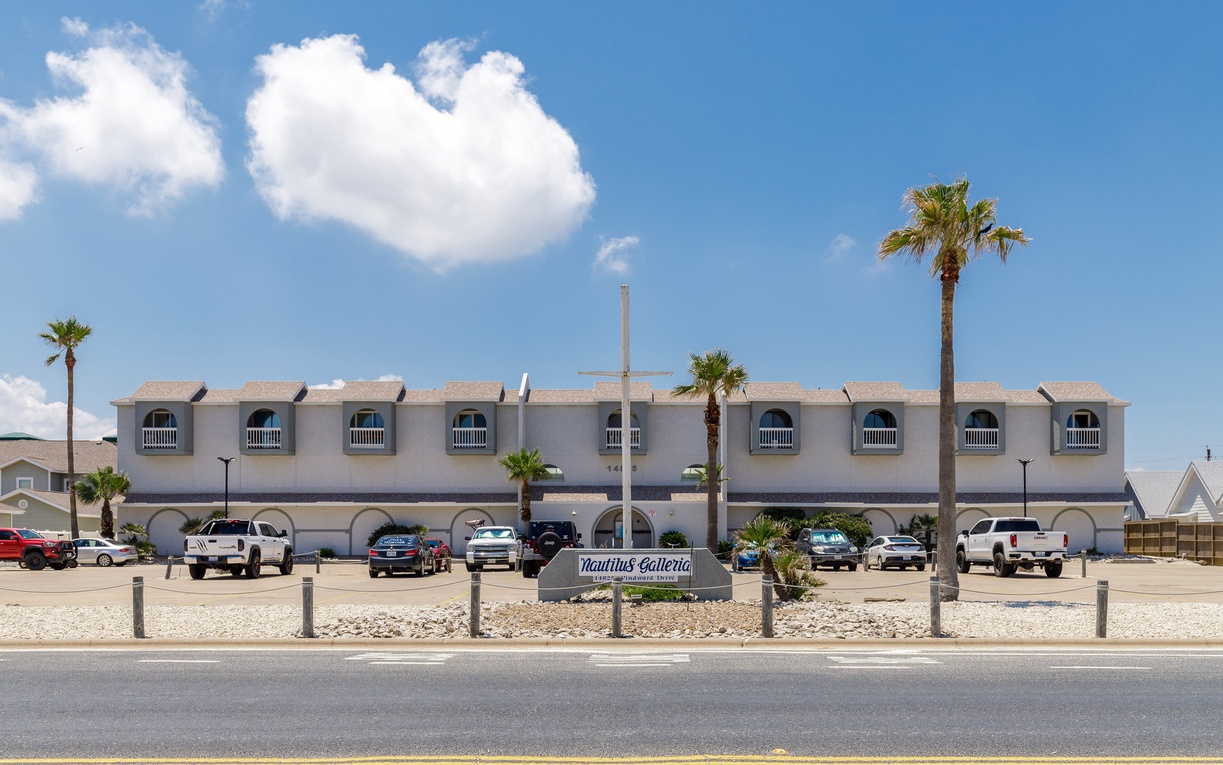 Nautilus Galleria offers a distinctive multi-unit vacation rental property with covered parking and tropical palm trees under bright blue skies.