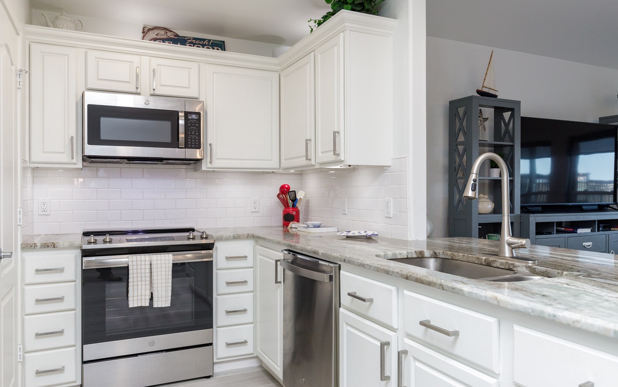 Your fully equipped kitchen with granite countertops, stainless steel appliances, and bright white cabinetry invites culinary adventures during your stay.