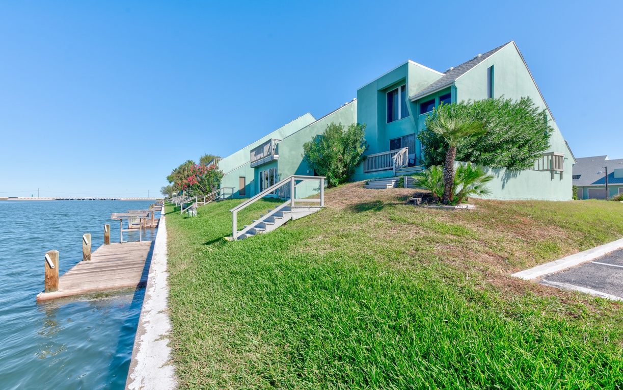 Waterfront property with private dock access and lush landscaping overlooking calm blue waters.