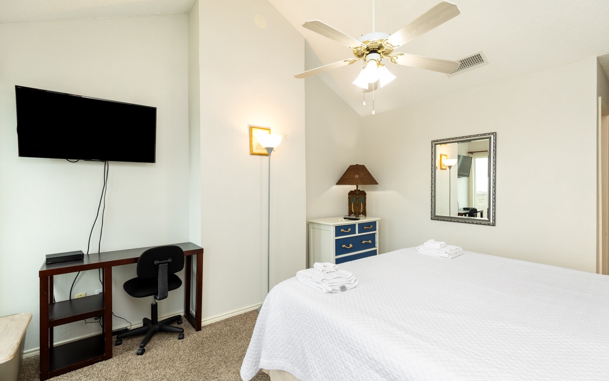 Relax in your bright, comfortable bedroom with plush bedding, convenient workspace, and entertainment ready for your stay.