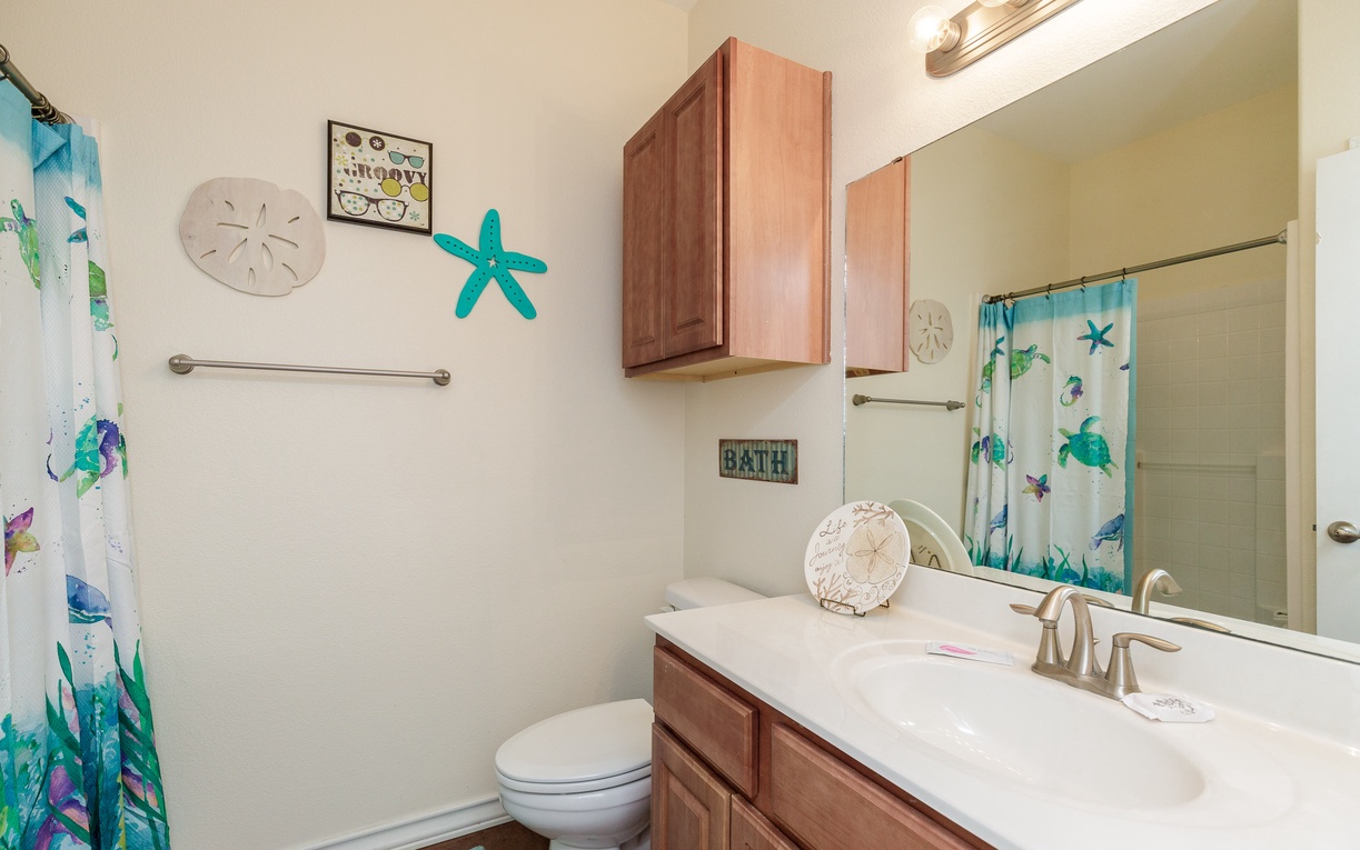 Refresh in your coastal-themed bathroom featuring cheerful ocean decor and tropical shower curtain that brings beachside vibes to your daily routine.