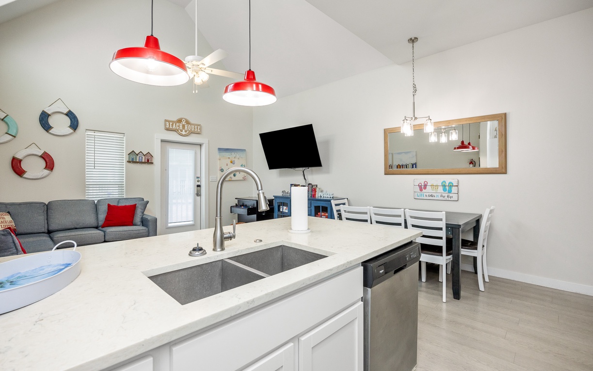 Your open-concept kitchen flows seamlessly into the living space, with modern appliances and cheerful red pendant lights creating a welcoming atmosphere for cooking and gathering.