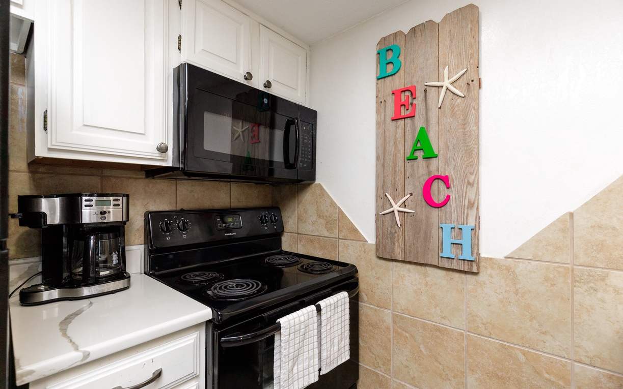 Cook your favorite meals in this fully equipped kitchen featuring modern appliances and charming beach-themed decor.