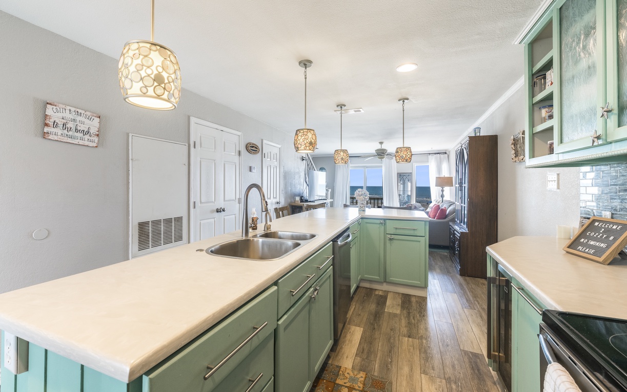 Cook your favorite meals in this spacious kitchen featuring mint green cabinets, elegant pendant lighting, and modern appliances.