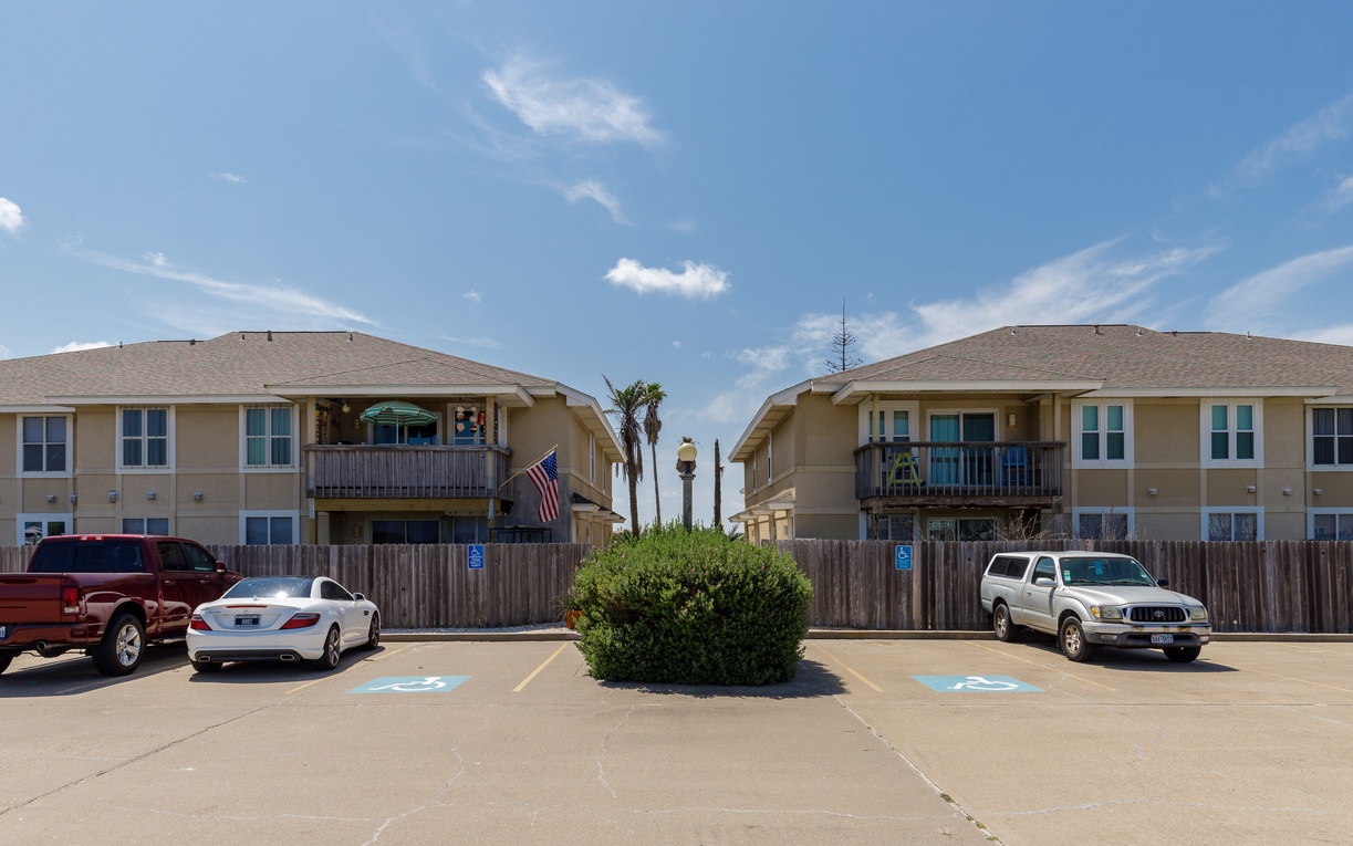 Beachside vacation rental complex with convenient parking and easy beach access via the nearby walkway.