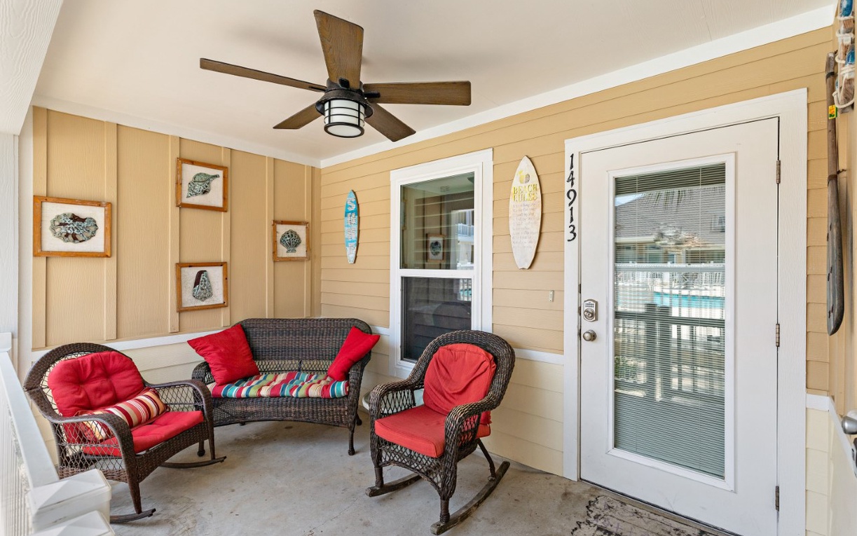 Relax on your covered porch with wicker seating and coastal decor, perfect for morning coffee or evening unwinding.