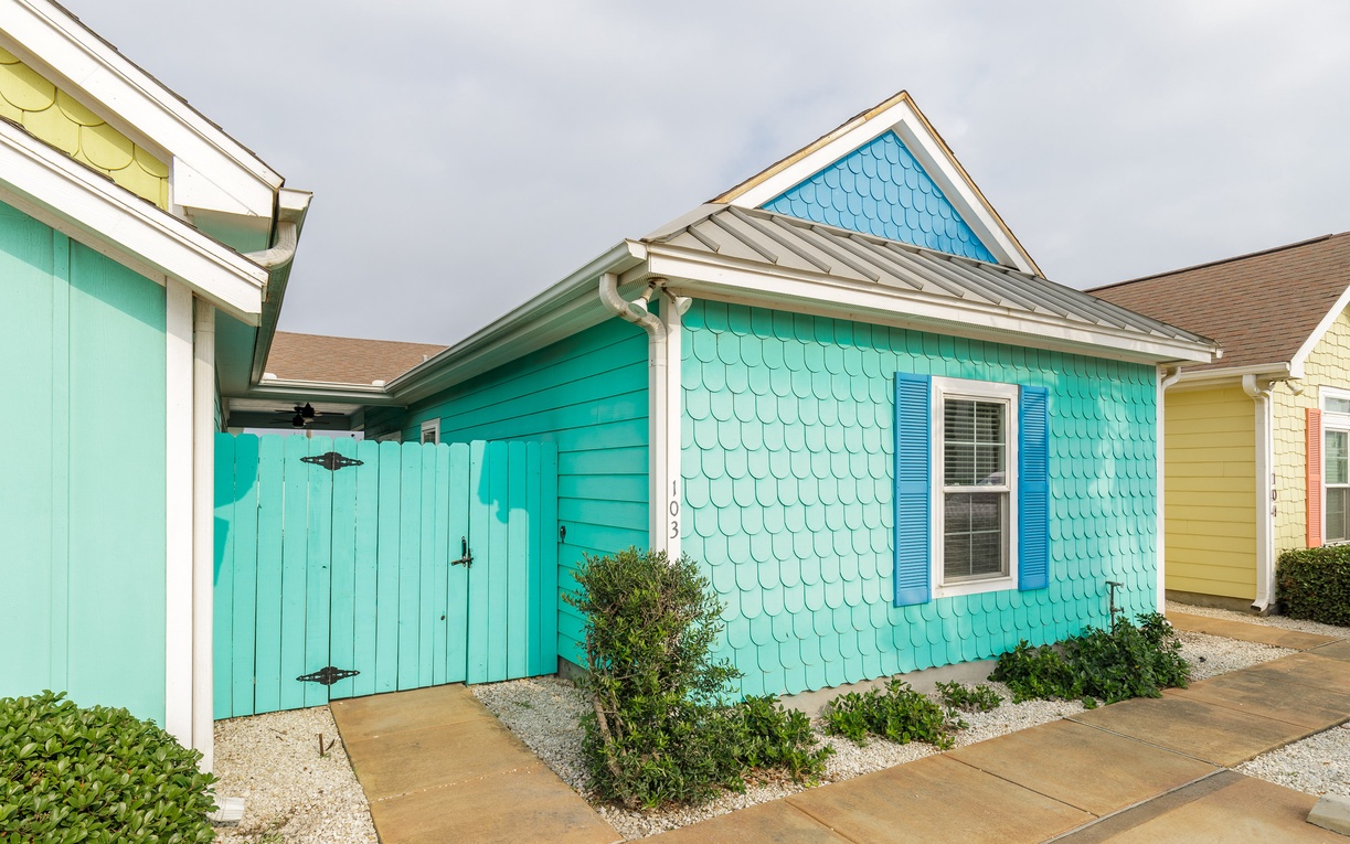 Charming coastal cottage with vibrant turquoise siding and unique shingle details creates a welcoming seaside retreat.
