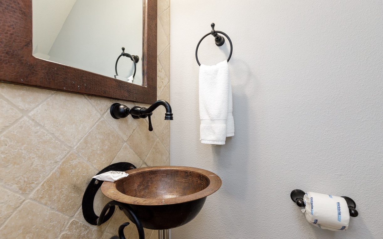 Refresh in your stylish copper sink with warm wood tones and crisp white towels waiting for you.