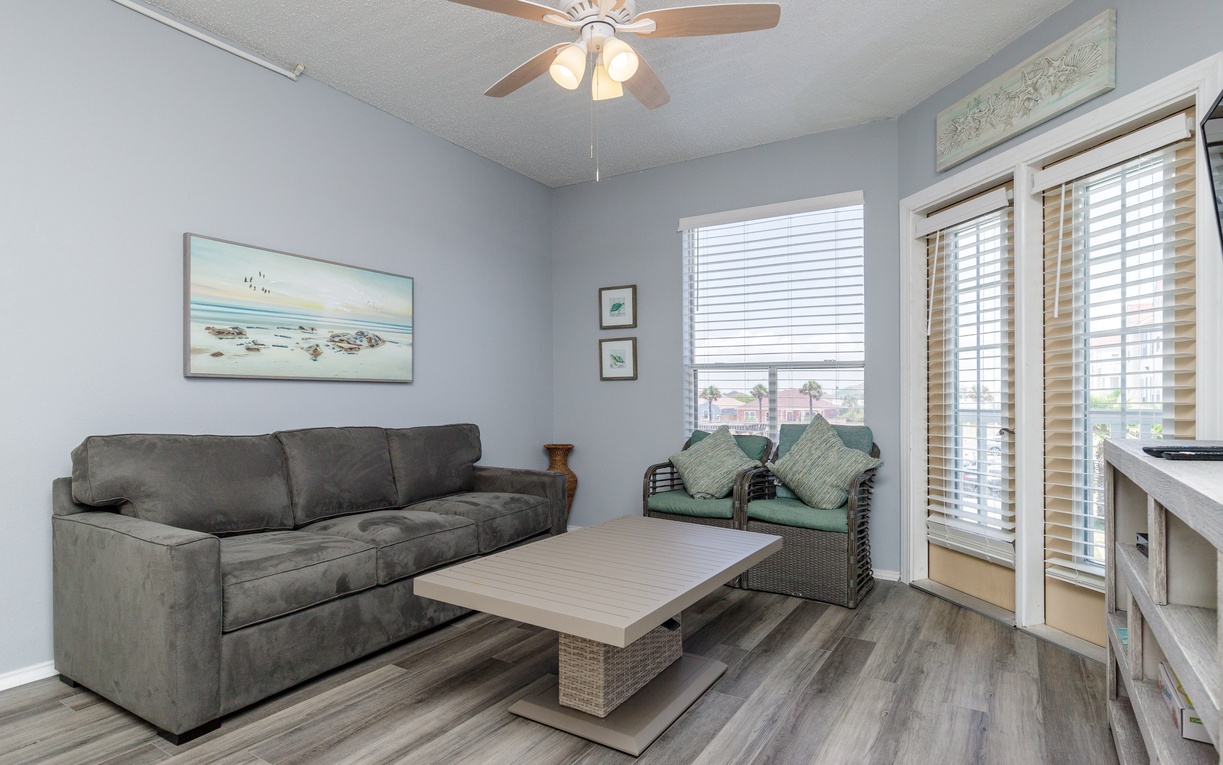 Relax in your bright living room with comfy sofa, coastal artwork, and peaceful balcony access for morning coffee.