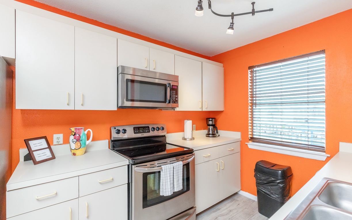 Bright orange walls energize your fully-equipped kitchen, featuring modern appliances and ample counter space for cooking your favorite meals.
