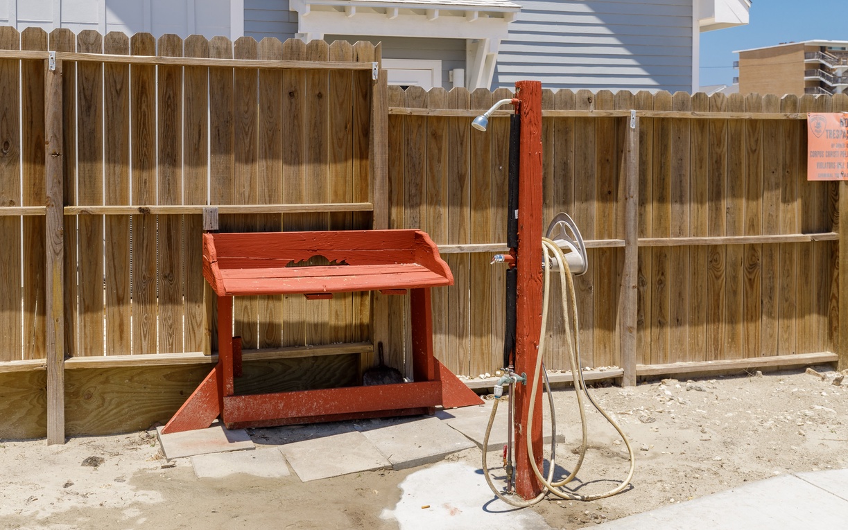 Rinse off after beach days at your private outdoor shower station with convenient storage bench.