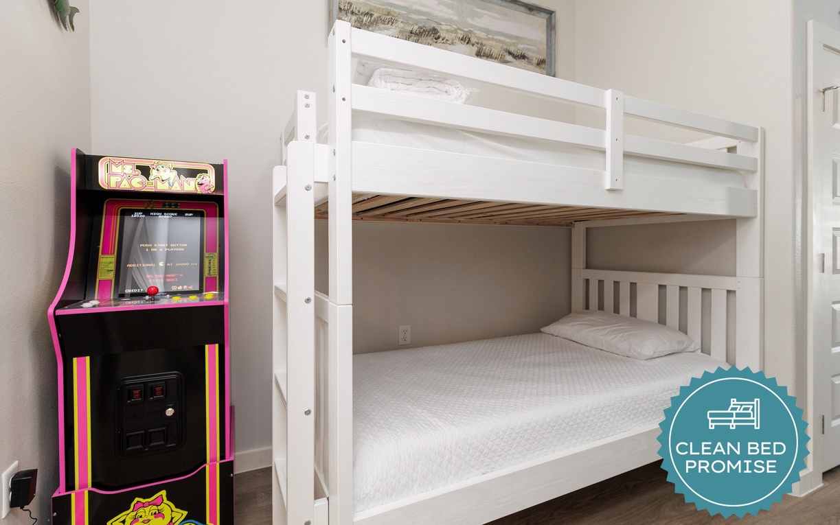 Your fun-filled bedroom features crisp white bunk beds and a vintage arcade machine for endless entertainment.