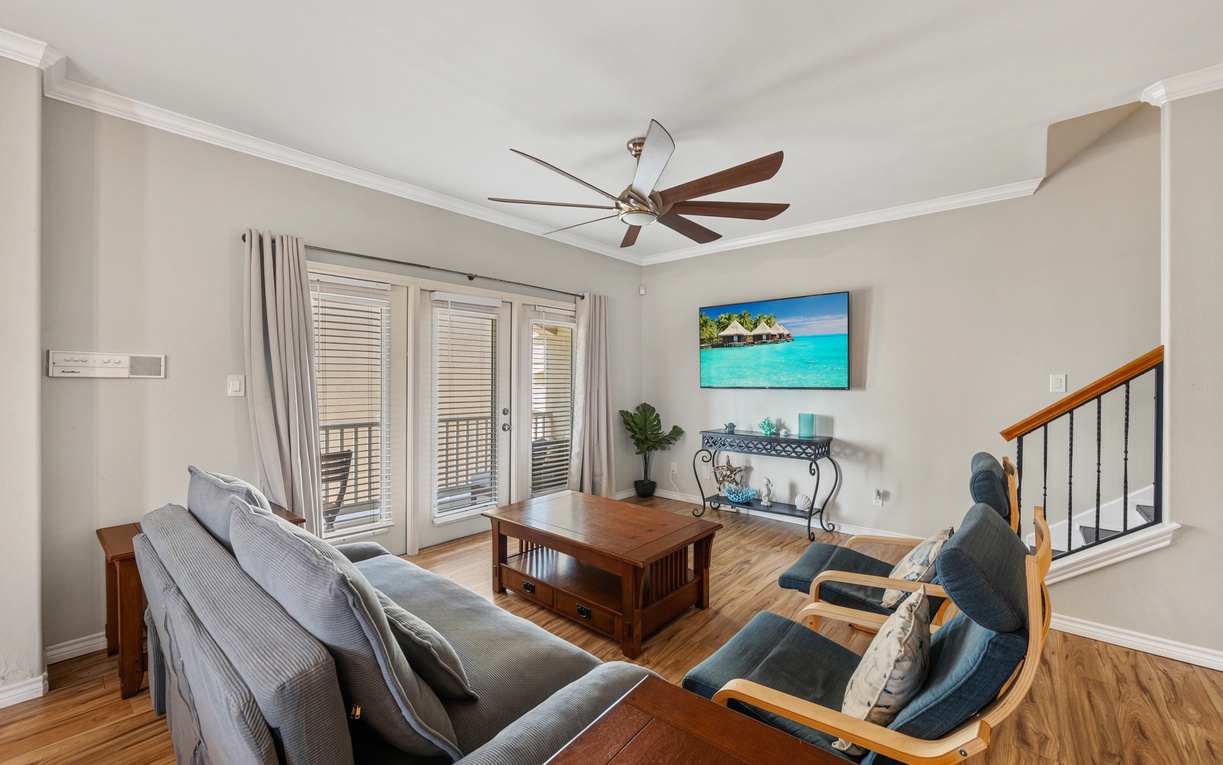 Unwind in your bright and airy living space where coastal-inspired decor meets comfort. Natural light streams through shuttered doors while the ceiling fan keeps things cool for your perfect retreat.