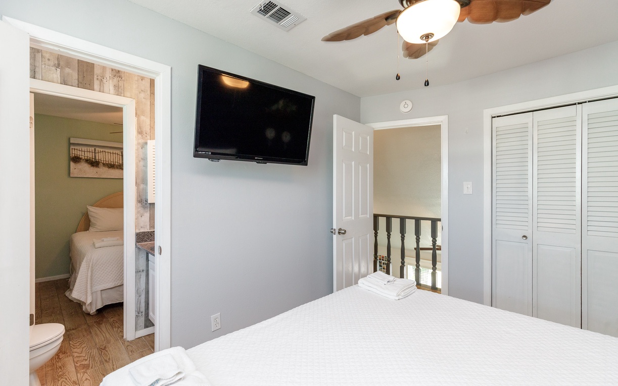 Your primary bedroom features cozy king linens, wall-mounted TV, and shared bathroom access.