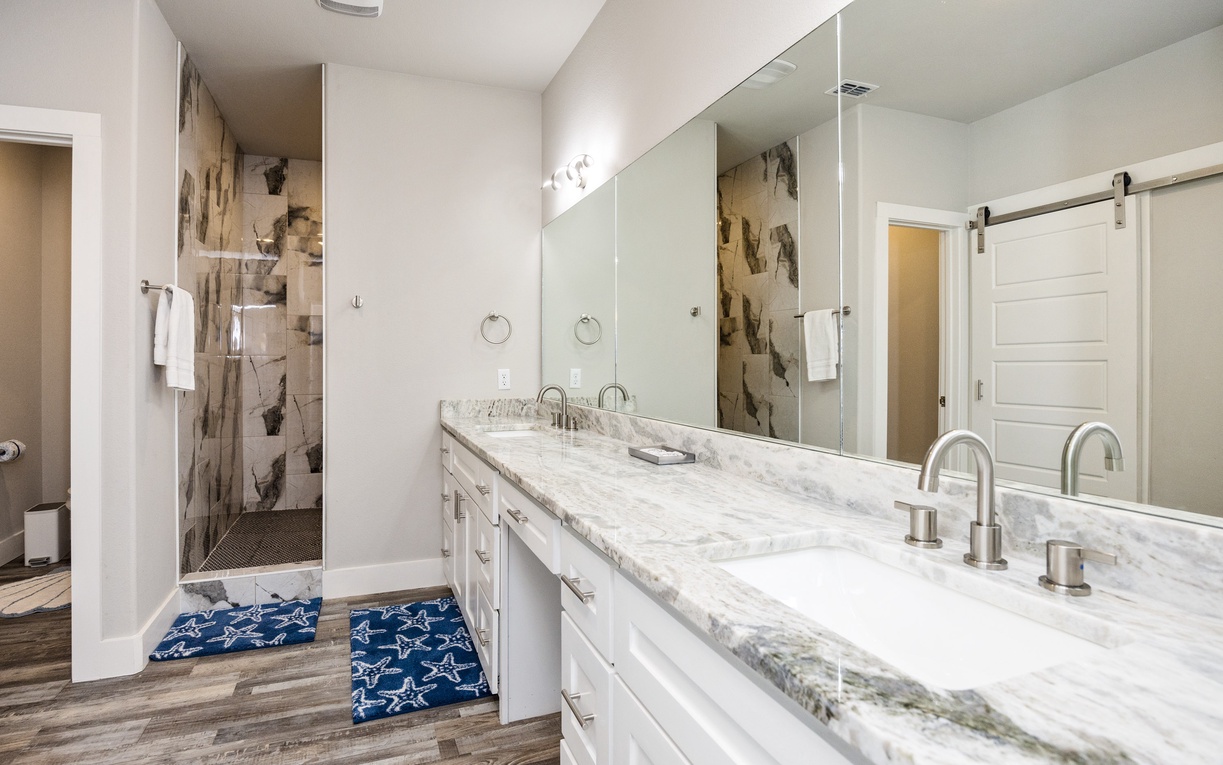 Unwind in your elegant marble vanity space with dual sinks and a luxurious walk-in shower featuring stunning stone accents.