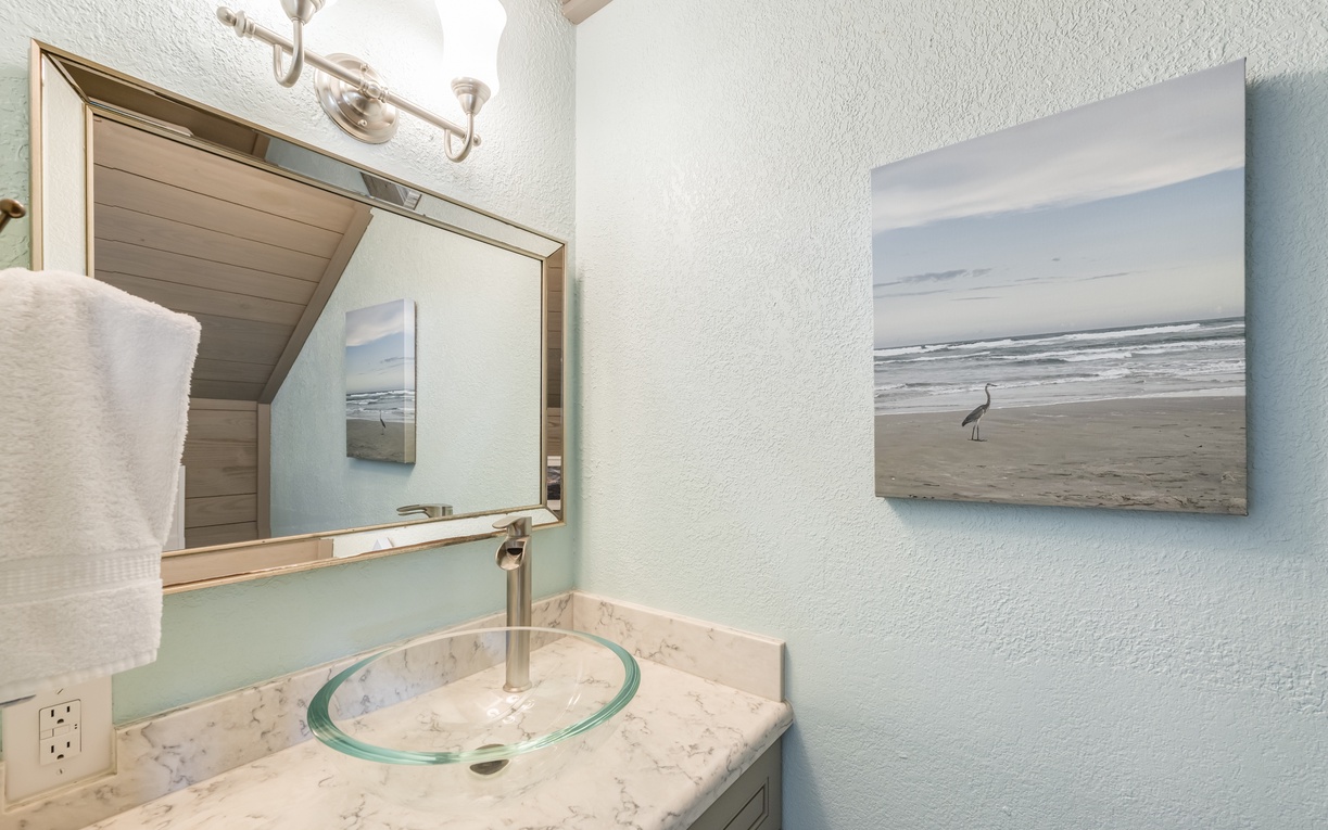 Freshen up in your coastal-inspired bathroom, where soft beach hues, elegant marble countertops, and serene artwork create a peaceful retreat after your day of exploring.