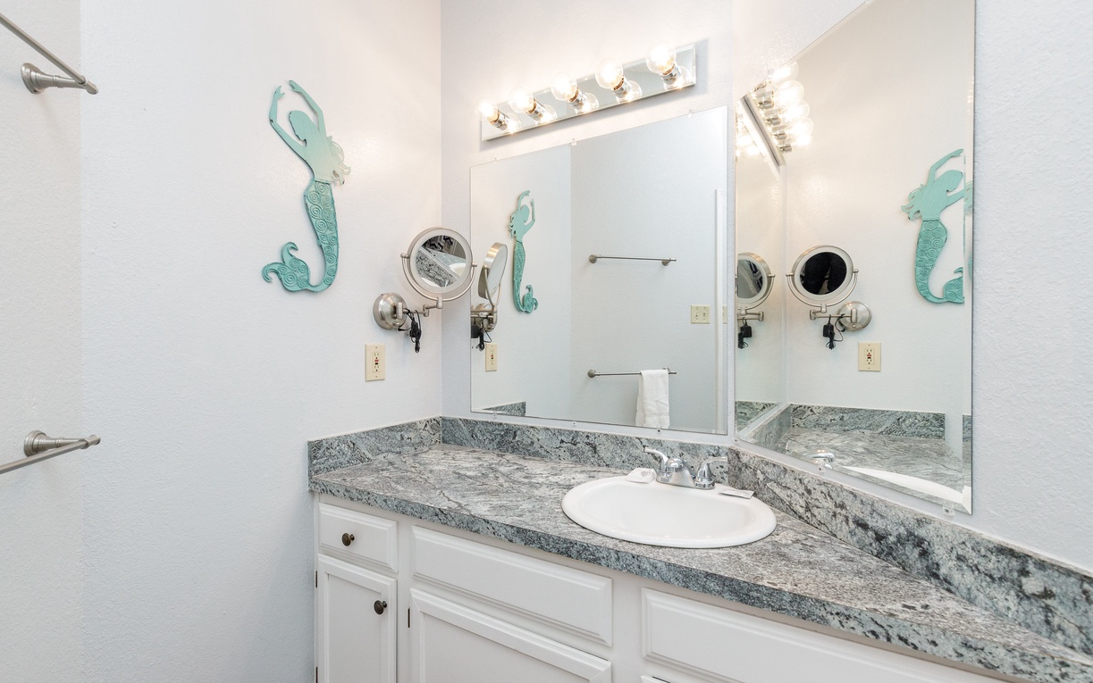 Your private bathroom features elegant granite counters and charming mermaid decor, creating a coastal oasis for your daily routines.