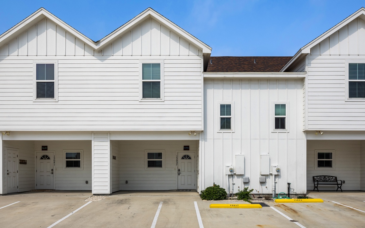 Modern white townhome complex with covered porches and convenient parking spaces for easy arrival.