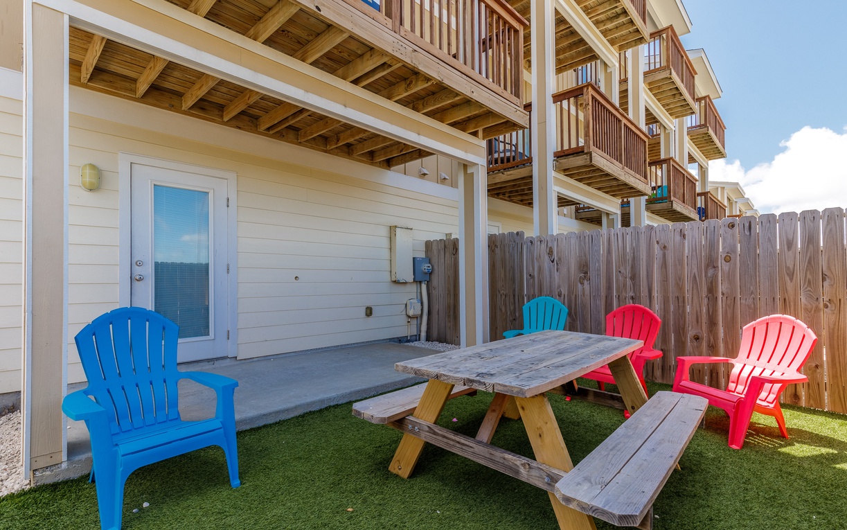 Your private patio features colorful Adirondack chairs and a picnic table, perfect for outdoor dining and relaxation.
