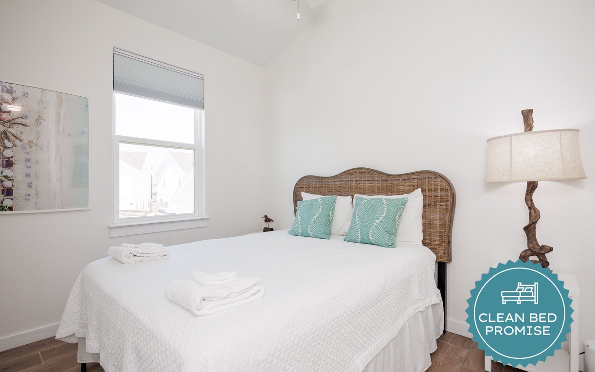 Your serene bedroom features a wicker headboard and turquoise accents, with crisp white linens waiting for your restful nights.