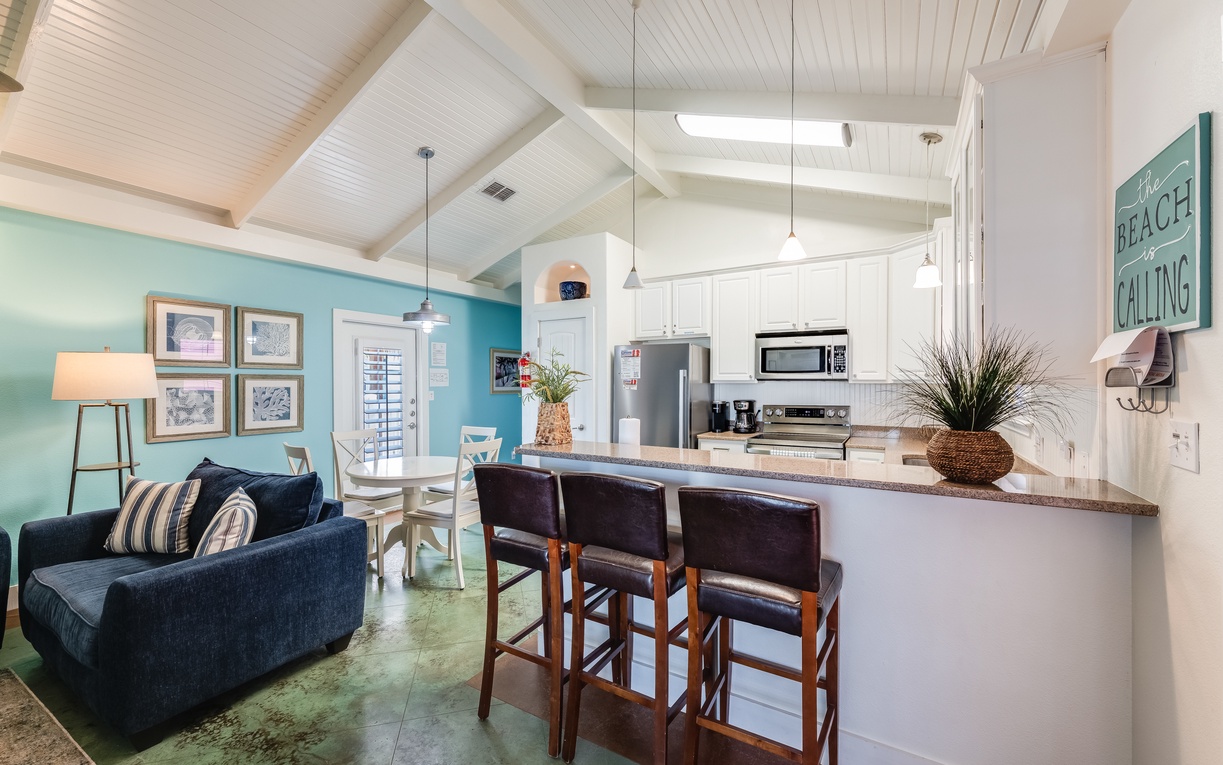 Relax in your coastal-inspired open living space with soaring beamed ceilings, fully equipped kitchen, and beach-themed décor perfect for vacation memories.