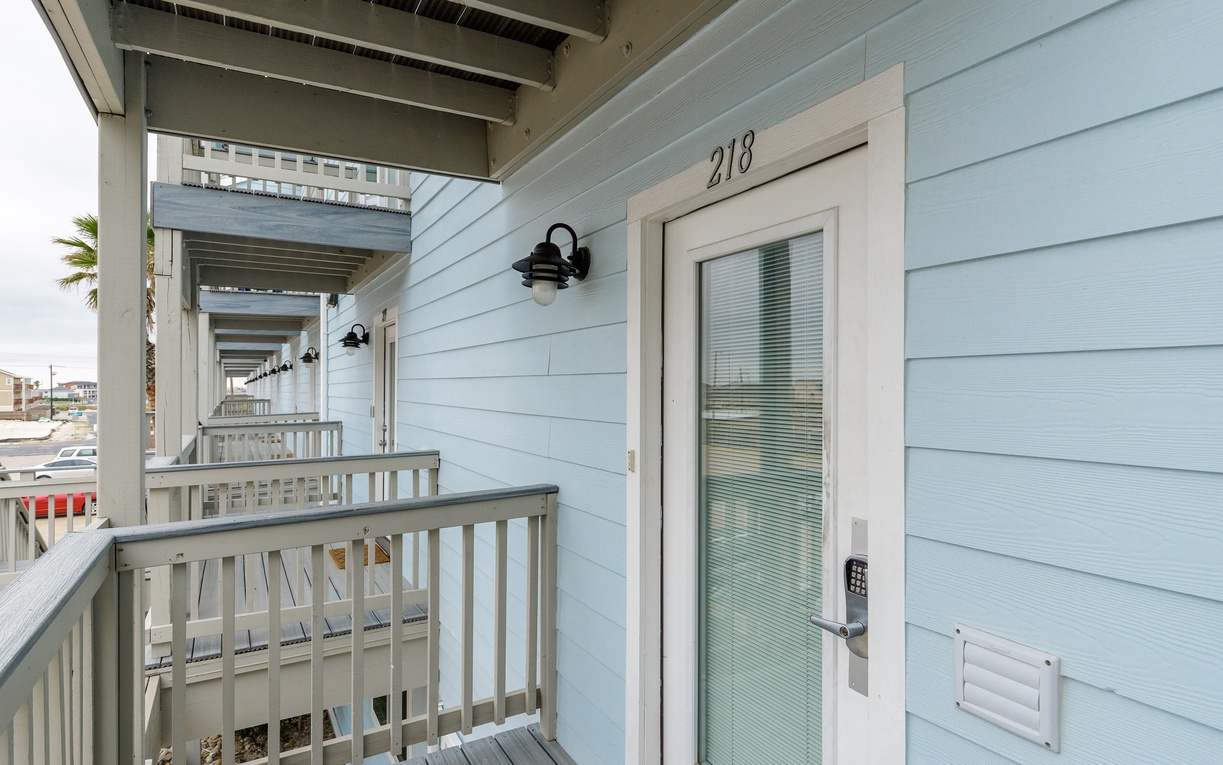 Coastal property entrance showing unit 218 with covered walkway access in a beachside community setting.