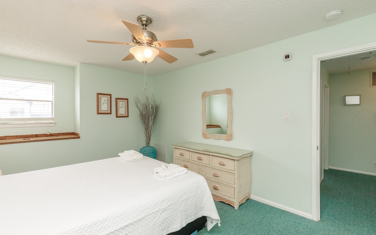 Relax in your peaceful bedroom with soft mint walls, a cozy ceiling fan, and fresh linens waiting for you.