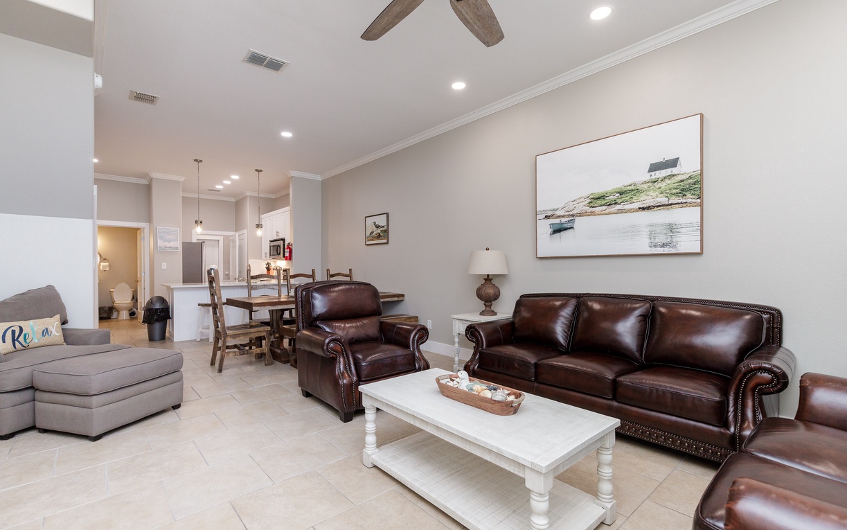 Sink into rich leather seating while you enjoy open-concept living, complete with modern kitchen and coastal artwork creating your perfect retreat.