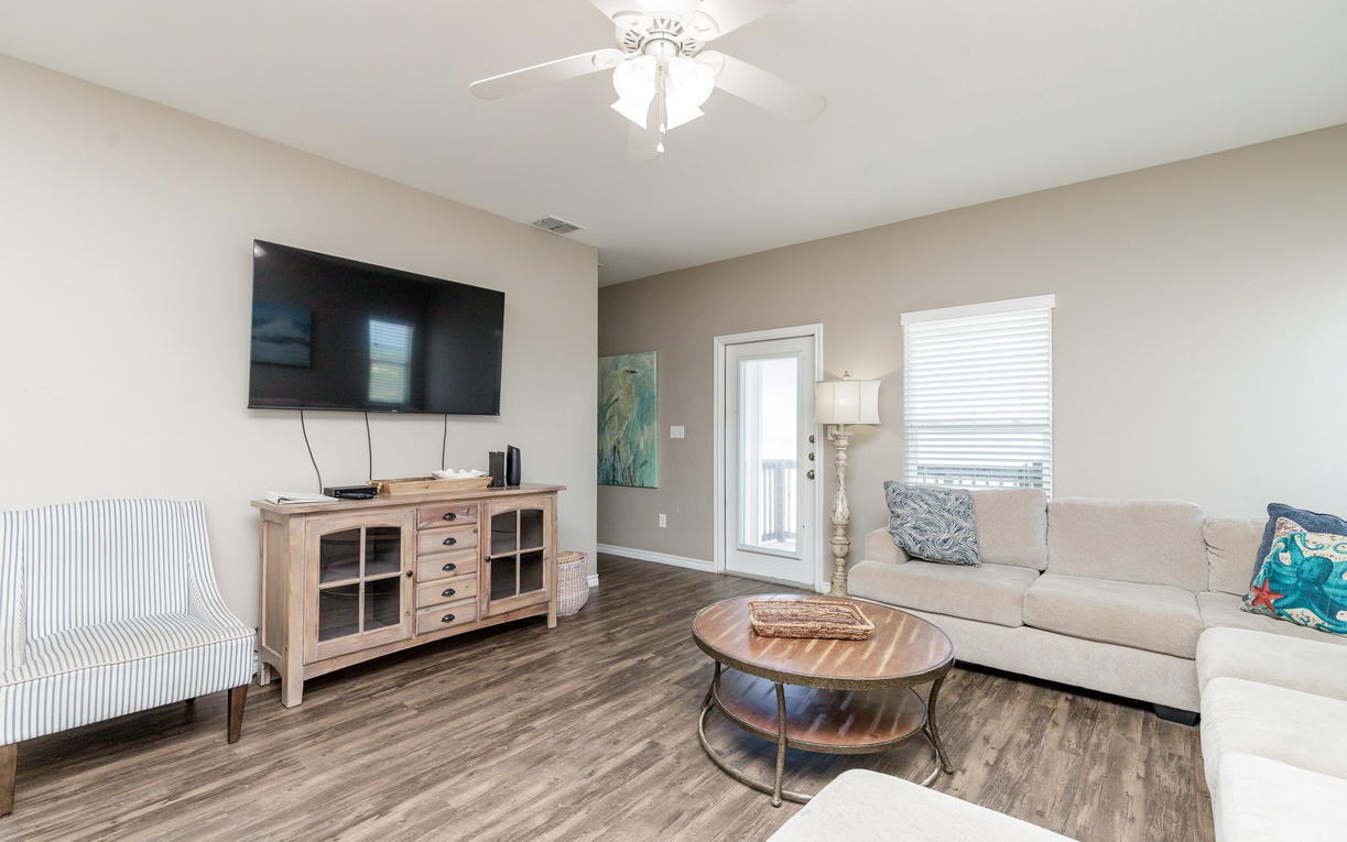 Relax in your spacious living room with plush seating, flat-screen TV, and natural light from the sliding door to your private balcony.