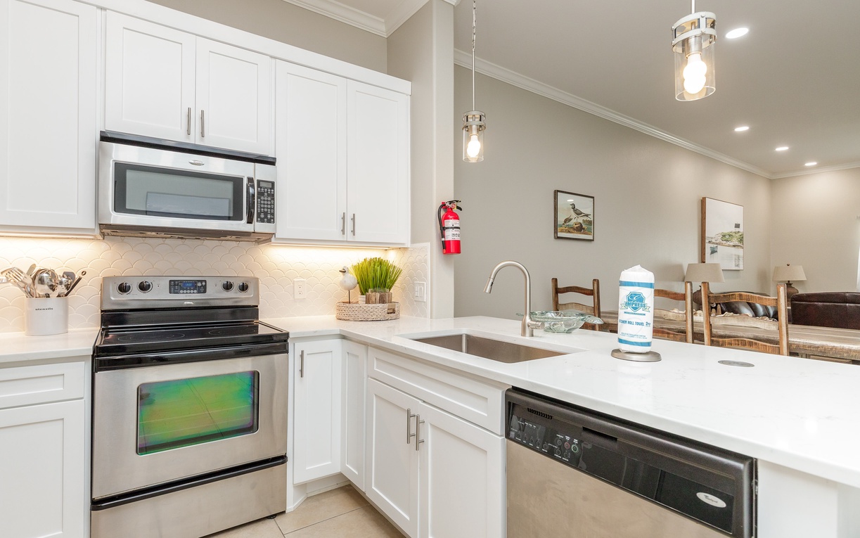 Cook your favorite meals in this bright, fully-equipped kitchen with modern appliances and elegant white cabinetry designed for your comfort.