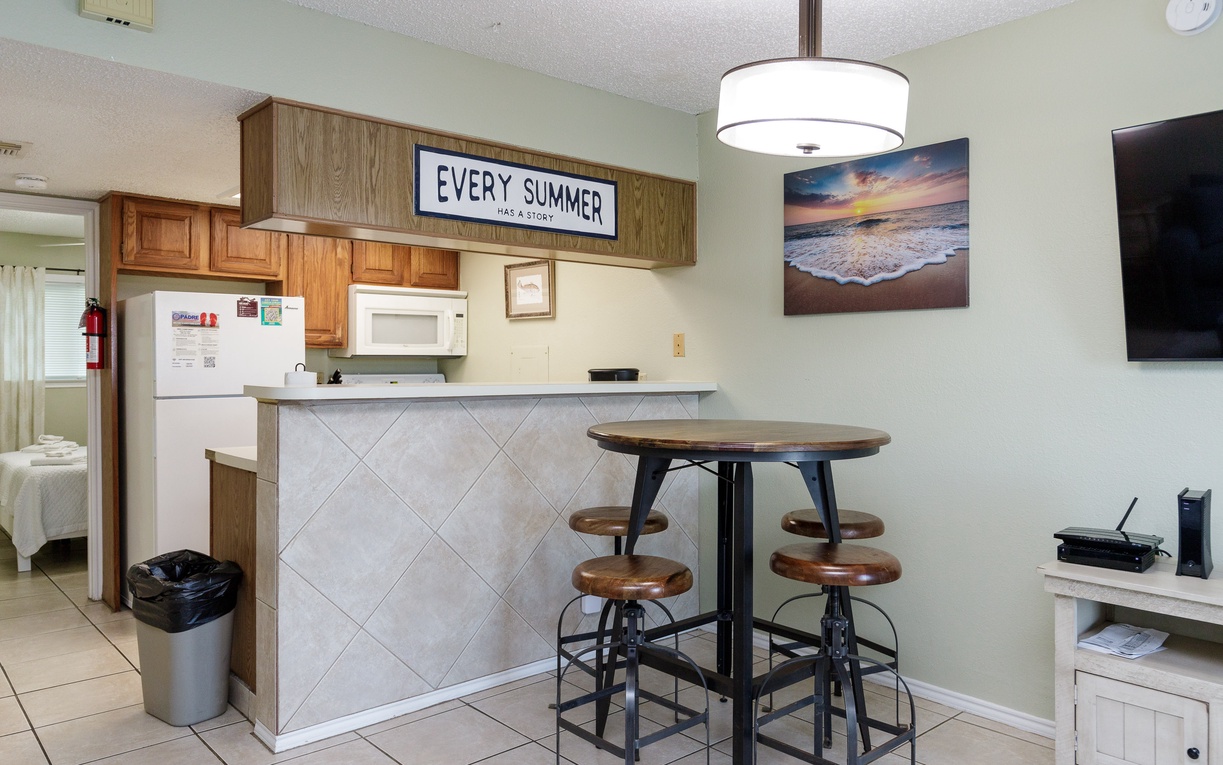 Your bright kitchen features coastal charm with beach artwork and a cozy breakfast bar for morning coffee.