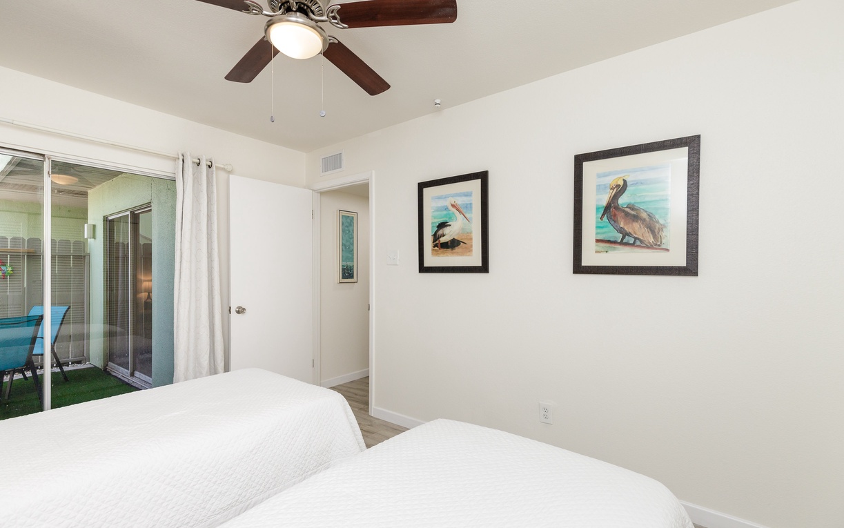 Rest peacefully in your bright bedroom, where coastal artwork and gentle ceiling fan breeze create the perfect seaside retreat atmosphere.