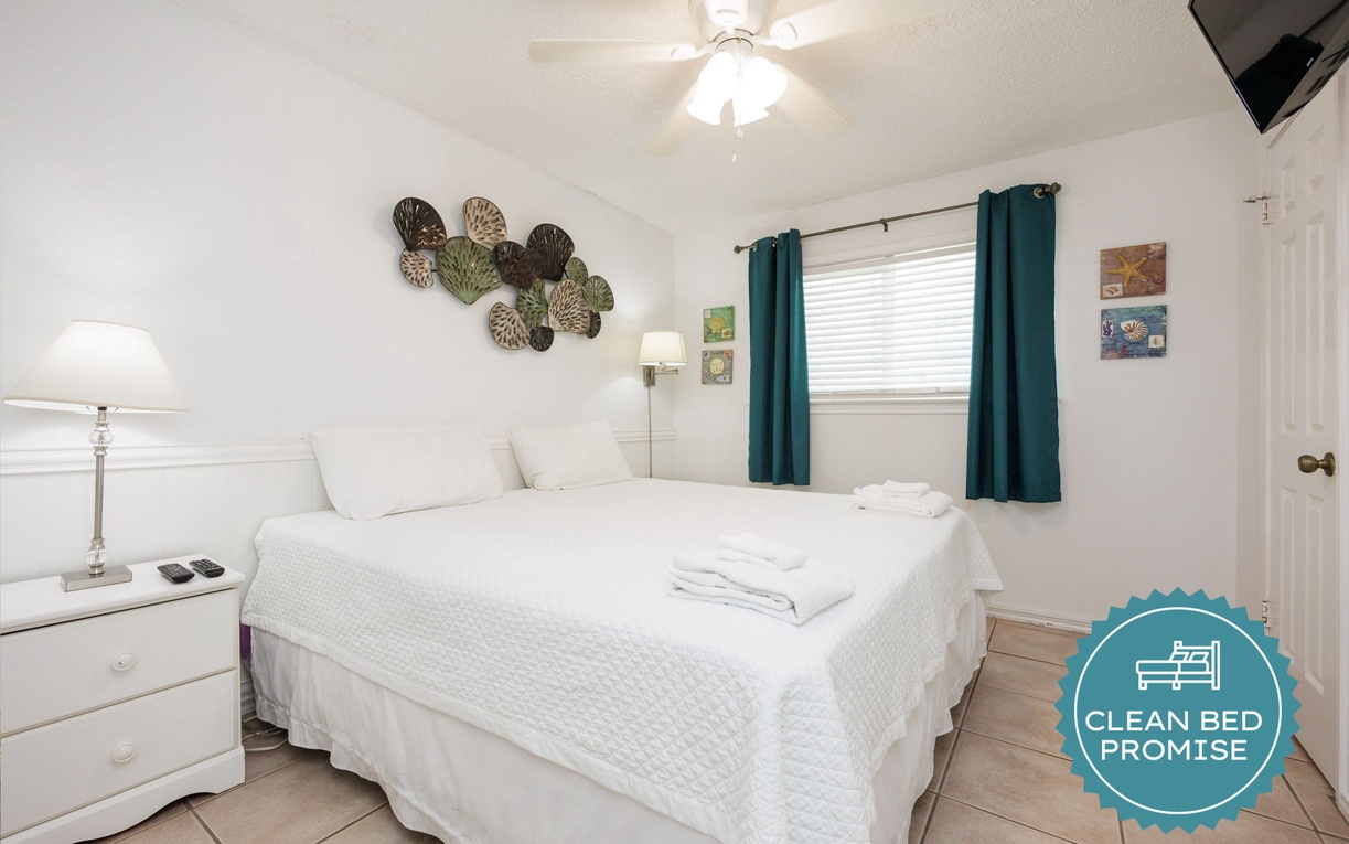 Rest peacefully in your serene bedroom with crisp linens, coastal decor, and natural light streaming through turquoise curtains.